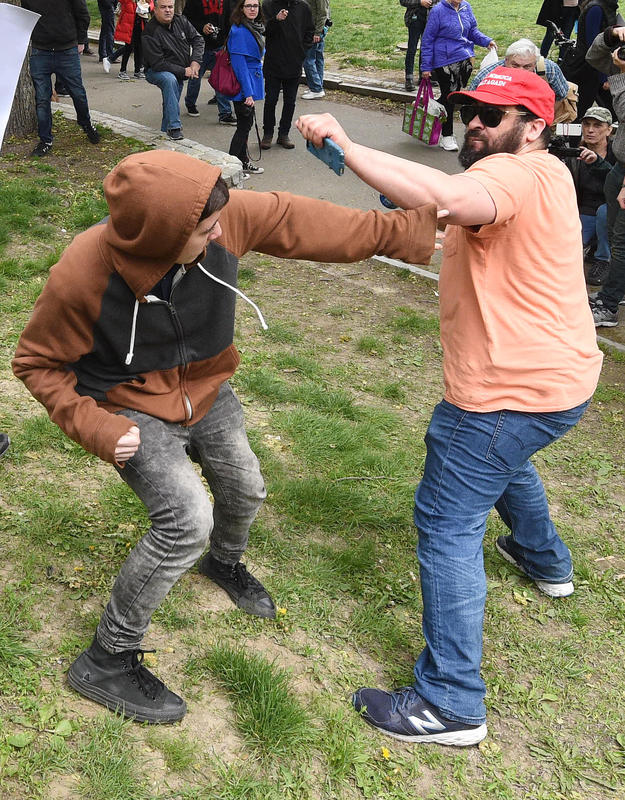 (Boston MA 05/13/17) A Trump supporter wearing a Make America Great Again cap, right, and a counter protester take a swing at each other,  after the Trump supporter used a Pepsi to taunt the anti-Trump protesters mimicking the Pepsi commercial with racial overtones, both were arrested, during a large demonstration on 6 different militias and a counter protest, Saturday, May 13, 2017, on the Boston Common.